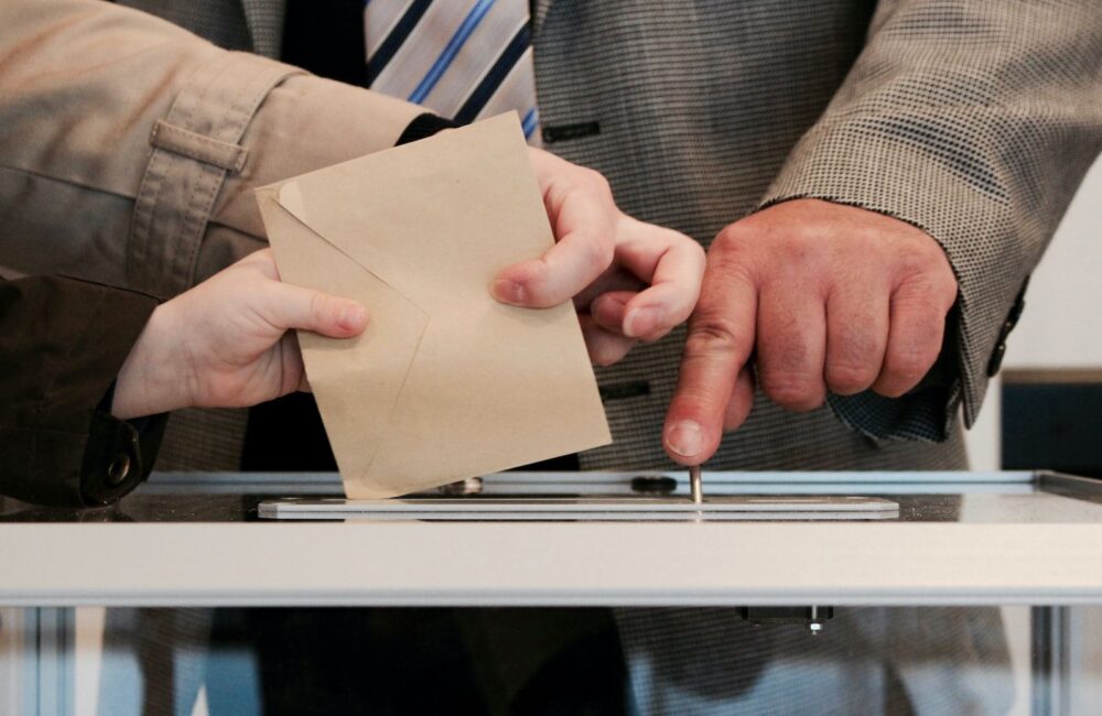 Gros plan sur enveloppe glissant dans urne transparente : le vote garant de la démocratie