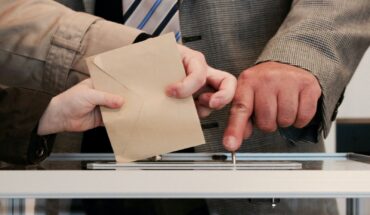 Gros plan sur enveloppe glissant dans urne transparente : le vote garant de la démocratie