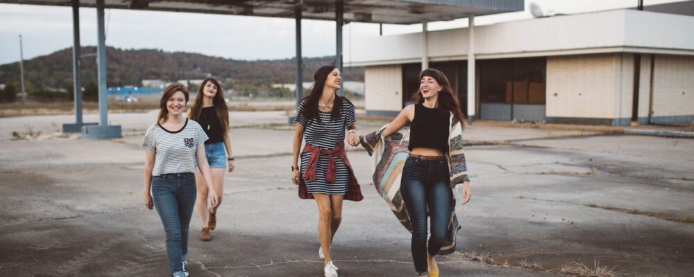 Quatre jeunes filles marchant sur un terre plein sur fond de bâtiment à l'abandon