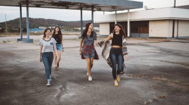 Quatre jeunes filles marchant sur un terre plein sur fond de bâtiment à l'abandon
