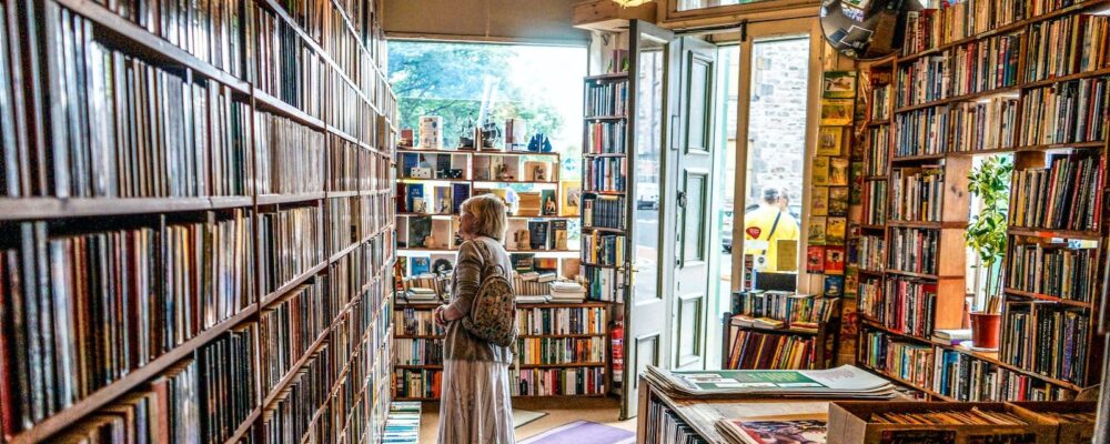 une femme cherche un livre dans un rayon de bibliothèque
